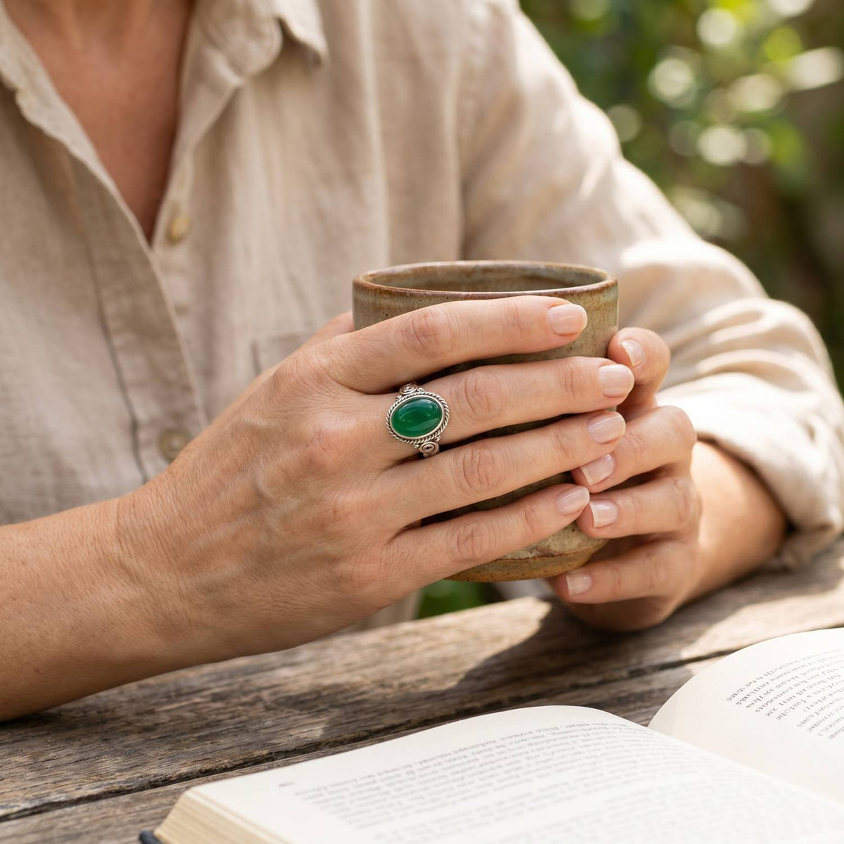 grüner Onyxring aus Silber getragen beim Lesen mit einer Tasse