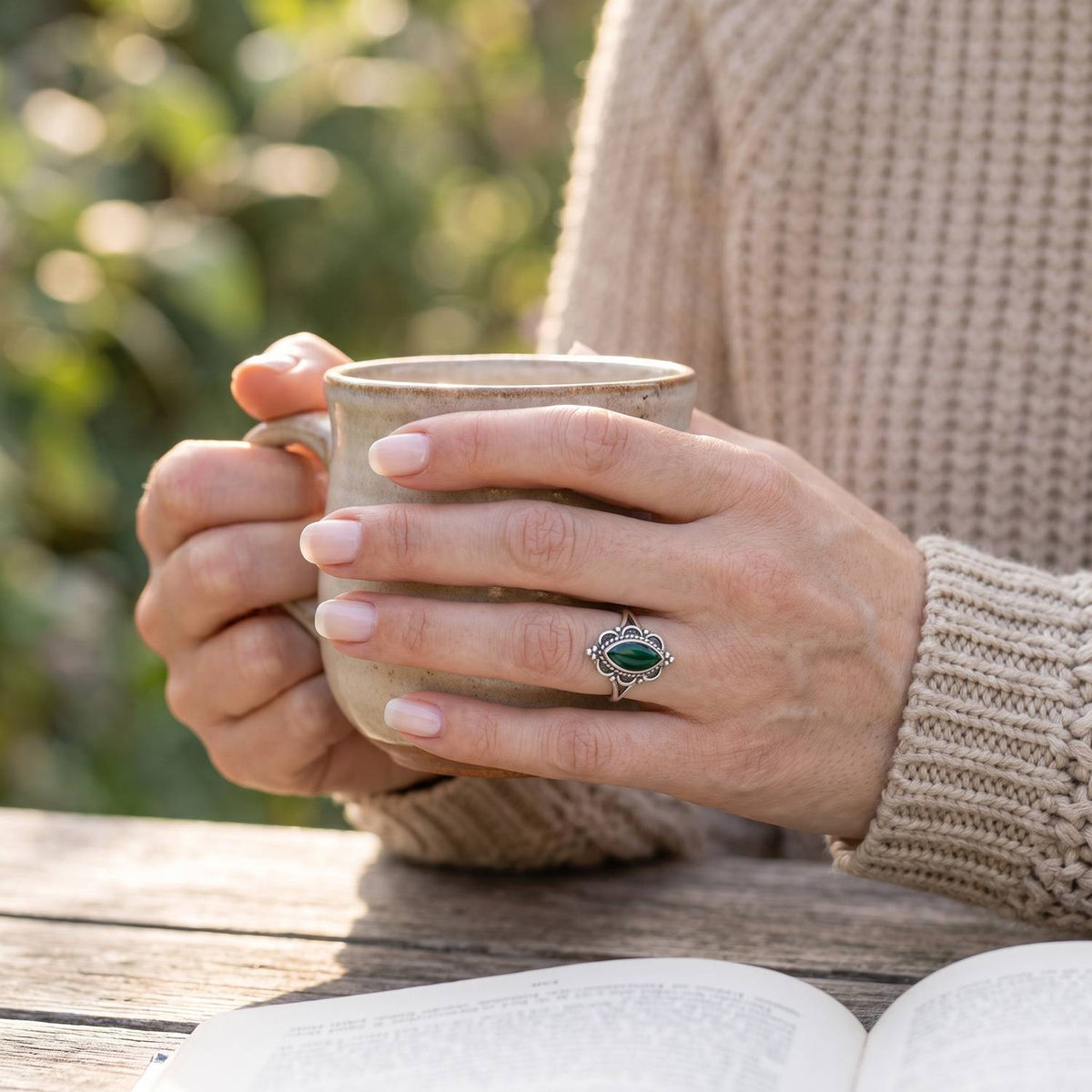 grüner Onyxring aus Silber getragen beim Lesen mit einer Tasse