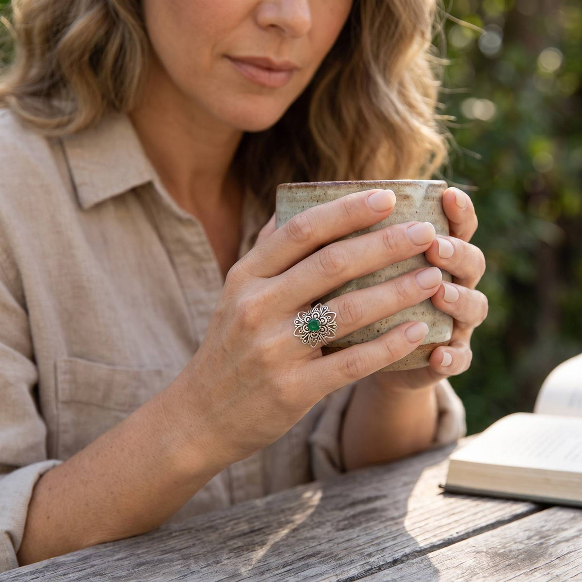 grüner Onyxring aus Silber getragen beim Lesen mit einer Tasse