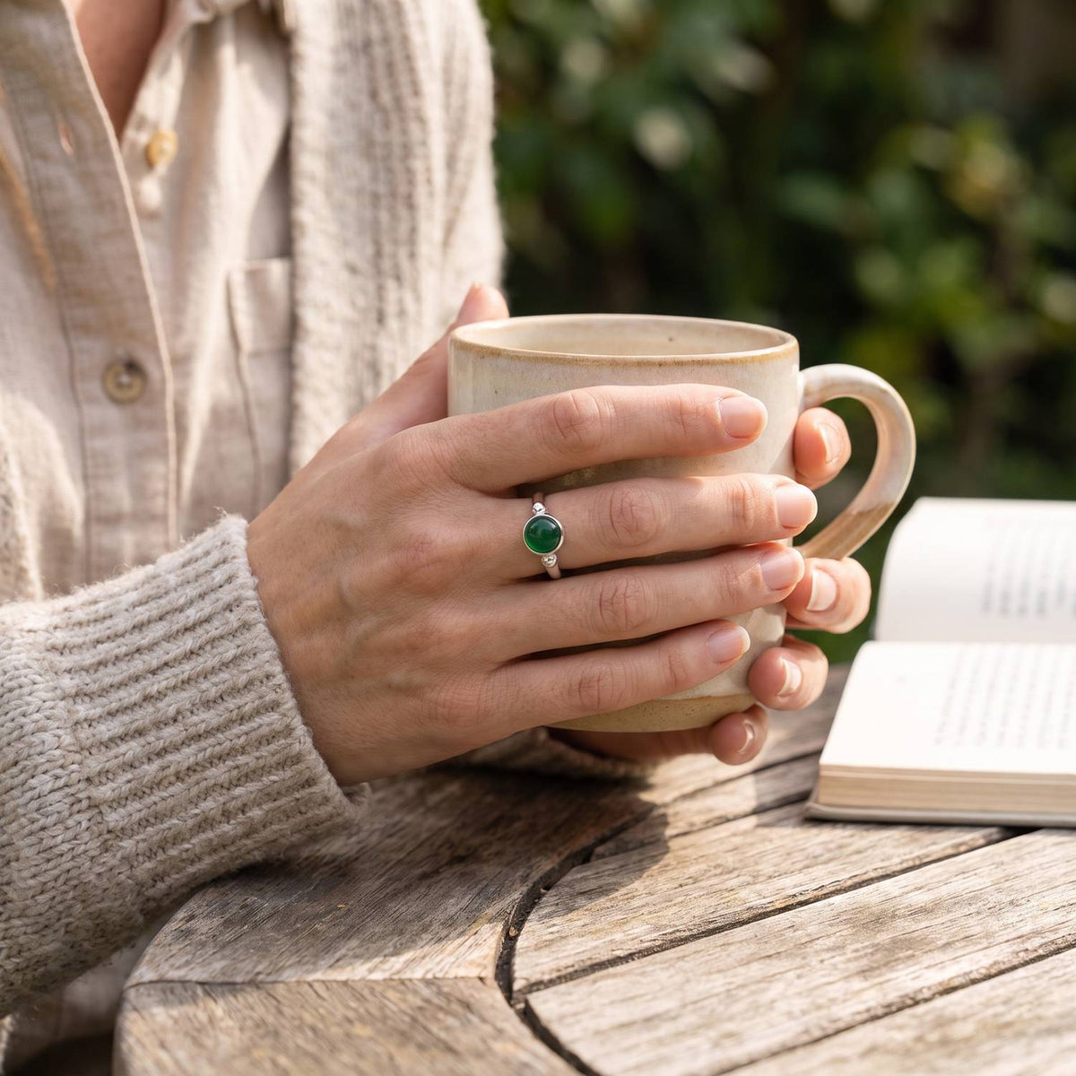 grüner Onyxring aus Silber getragen beim Lesen mit einer Tasse