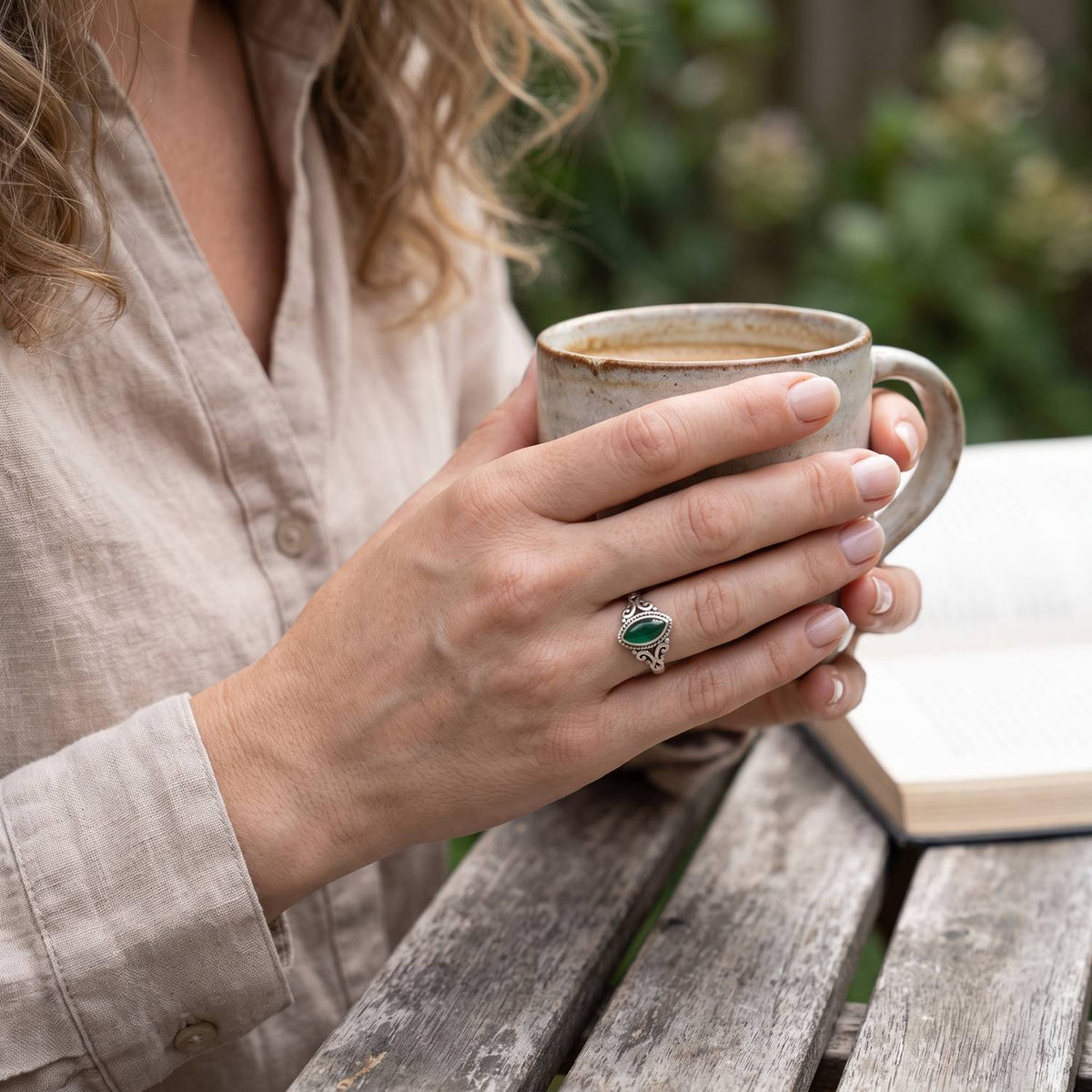 grüner Onyxring aus Silber getragen beim Lesen mit einer Tasse