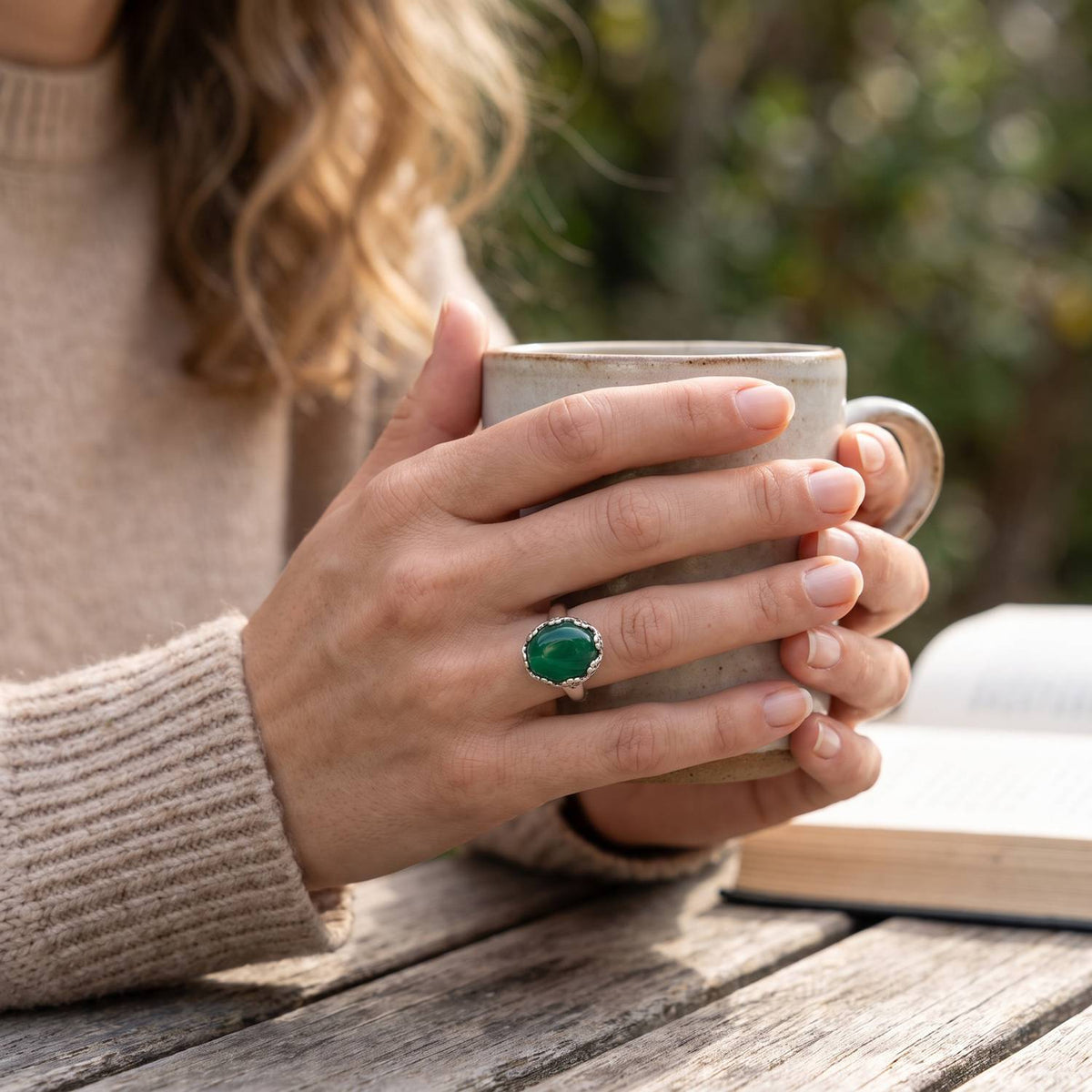 grüner Onyxring aus Silber getragen beim Lesen mit einer Tasse