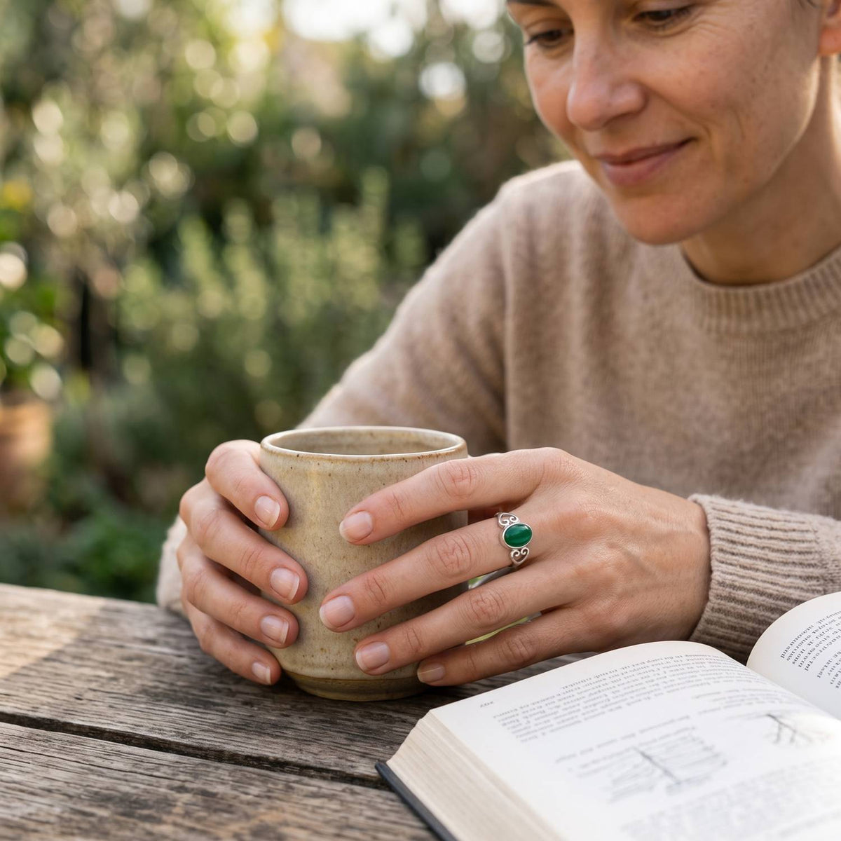 grüner Onyxring aus Silber getragen beim Lesen mit einer Tasse