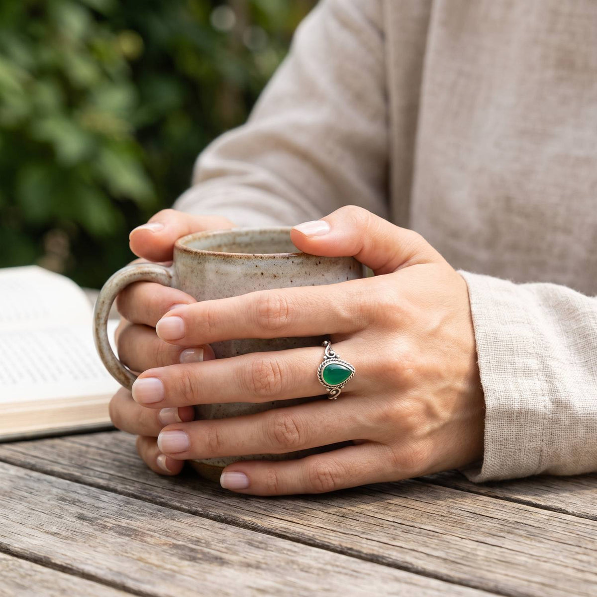 grüner Onyxring aus Silber getragen beim Lesen mit einer Tasse