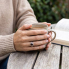 [KI] Granatring aus Silber getragen beim Lesen mit einer Tasse