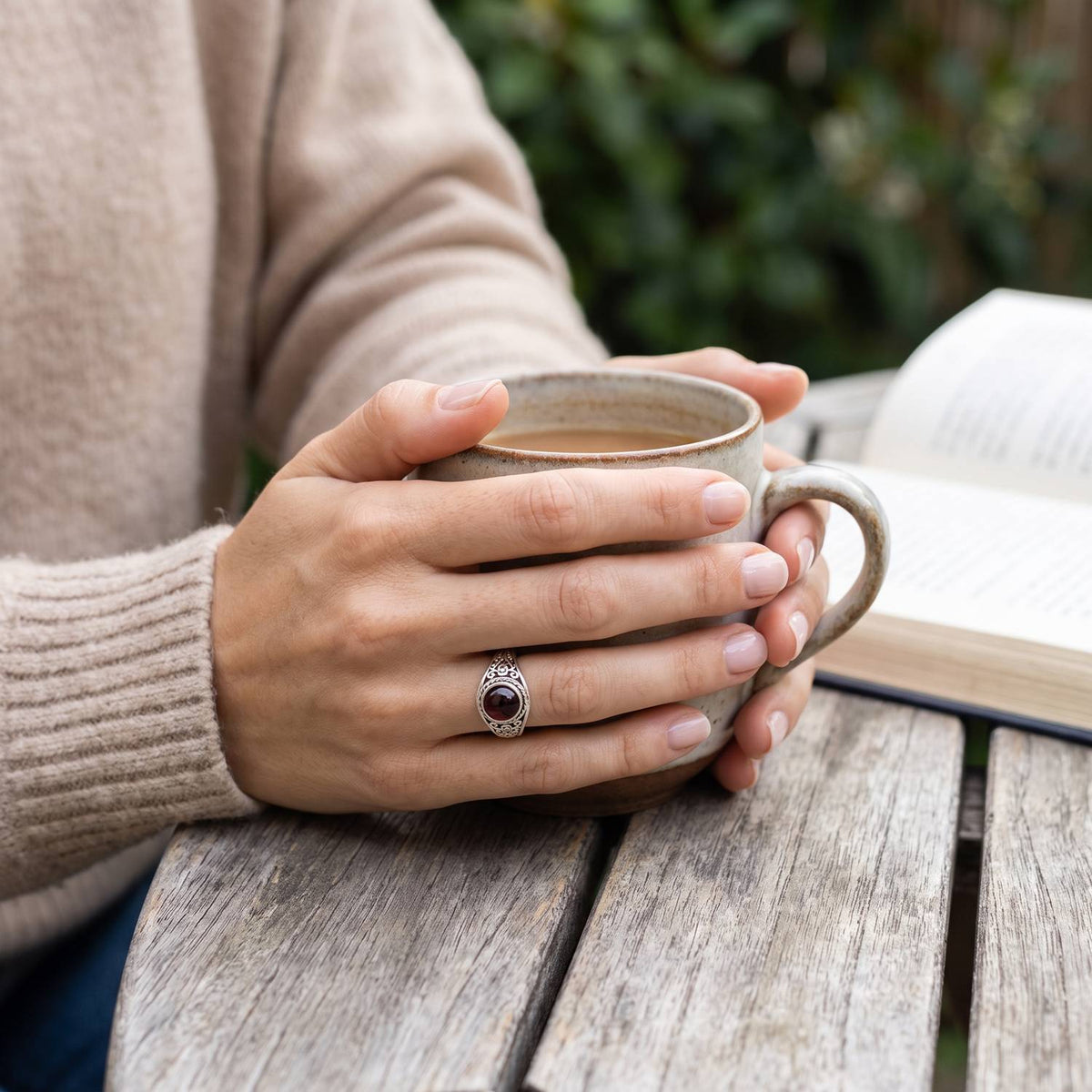 Granatring aus Silber getragen beim Lesen mit einer Tasse