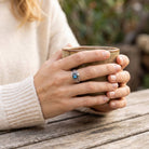 [KI] Labradoritring aus Silber getragen beim Lesen mit einer Tasse