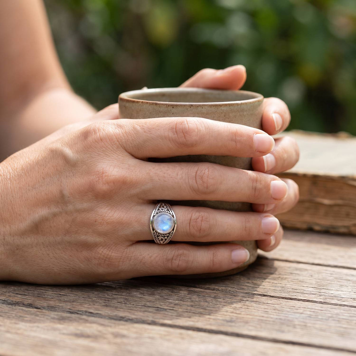 Mondsteinring aus Silber getragen beim Lesen mit einer Tasse